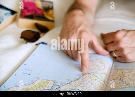 Dito di un uomo che punta verso la posizione sulla mappa aperta Foto Stock