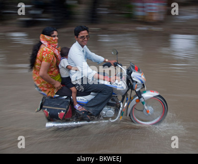 India, Uttar Pradesh, Agra, motociclista e passeggeri in forti piogge monsoniche passeggiate a cavallo nel diluvio Foto Stock