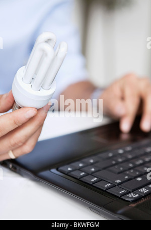 Primo piano sul basso-enegry lampadina e il computer portatile Foto Stock