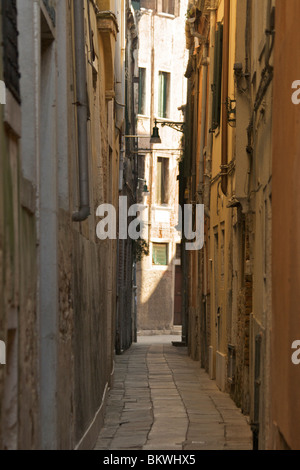 Ombreggiata veneziano stretta strada pedonale - Salizada Malipiero - con bandiere e di edifici alti Foto Stock