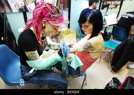 Donna artista tattooist lavorando su un nuovo tattoo per la giovane donna. Tattoo Convention di Roma 2010. Foto Stock