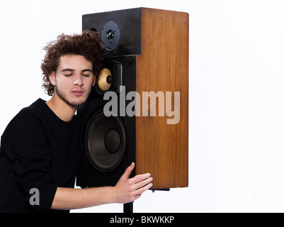 Studio ritratto di una giovane caucasico uomo ascolto di amanti della musica con il telefono vivavoce isolati su sfondo bianco Foto Stock