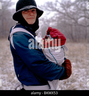 La madre che porta il suo bambino neonato figlio sulla passeggiata invernale innevato attraverso i campi agricoli, Montgomery County, Pennsylvania, STATI UNITI D'AMERICA Foto Stock