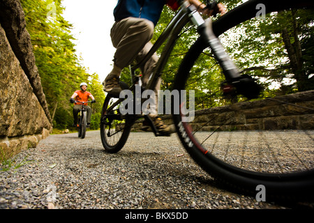 Due uomini in bicicletta su una strada carrozzabile vicino Jordan Pond nel Maine il Parco Nazionale di Acadia. Foto Stock