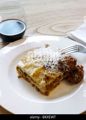 Italiano tradizionale piatto di lasagne con ragù di carne e un bicchiere di vino nella parte in Italia Foto Stock