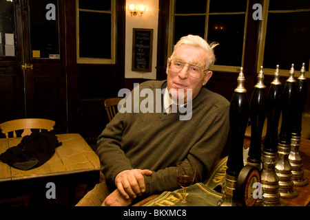 Seduto senior l uomo si appoggia sulla barra in un pub inglese Foto Stock