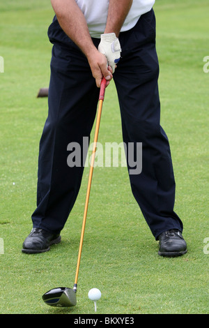 Giocatore di golf tees fino con il suo autista sul raccordo a T Foto Stock