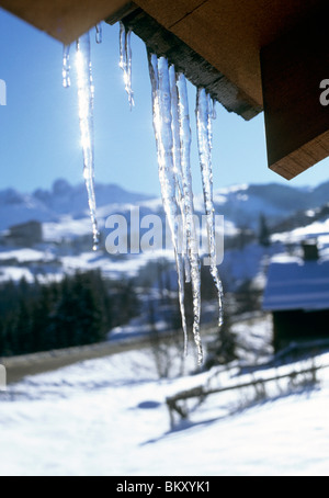 Ghiaccioli pendenti dal tetto mentre il sole splende attraverso Foto Stock