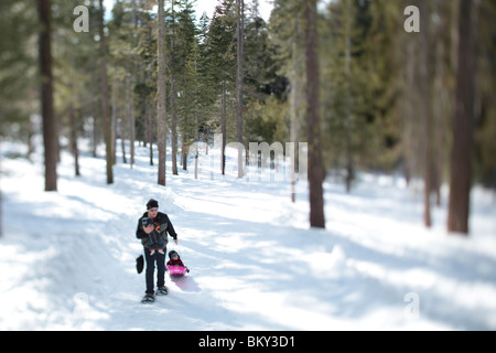 Un padre con le racchette da neve con un neonato e un bambino nella coperta di neve deserto di Lake Tahoe, Calfornia. Foto Stock