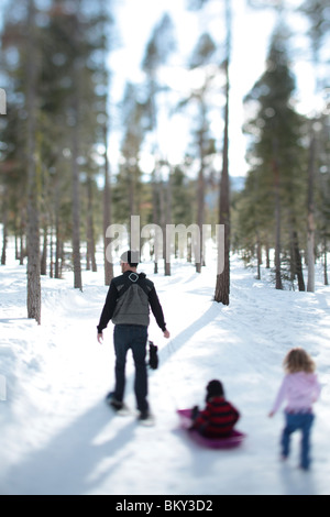 Un padre con le racchette da neve con un neonato e un bambino nella coperta di neve deserto di Lake Tahoe, Calfornia. Foto Stock