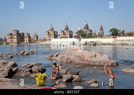 La gente la balneazione nel fiume Petwa.sullo sfondo il Royal cenotaphs. Orchha. Il Madhya Pradesh. India Foto Stock