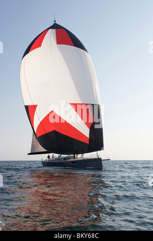 Un equipaggio gare un moderno oceaniche yacht a vela sotto spinnaker. Foto Stock