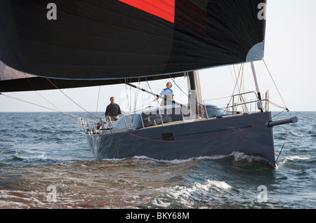 Un equipaggio gare un moderno oceaniche yacht a vela sotto spinnaker. Foto Stock