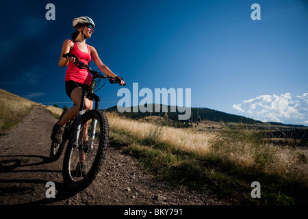 Una femmina di mountain biker si ferma per godere la vista mentre cavalcate i sentieri di Mt. Sentinella, Missoula, Montana. Foto Stock