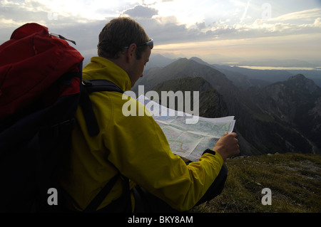 Escursionista con zaino in spalla e la mappa dei sentieri di sera, Klammspitze, Alpi Ammergau, Baviera, Germania, Europa Foto Stock