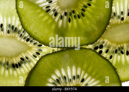 Quattro fette sottili di kiwi in stretta che mostra i semi. Illuminato da dietro per sottolineare la forma delle cellule. Foto Stock