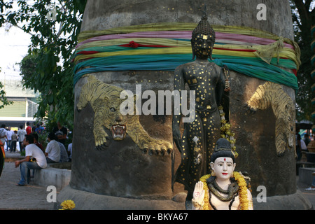 Statua di Shiva e il Buddha di fronte una campana di Wat Phra Bang, un tempio buddista in Thailandia dove i monaci devoti del tatuaggio. Foto Stock