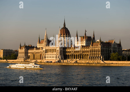 Il Parlamento europeo e il fiume Danubio con barca, una barca di svago sul fiume Danubio passando il Parlamento, Pest, Budapest, Ungheria Foto Stock