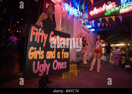 Tre go-go le ragazze nella parte anteriore di un nightclub, una donna tenendo un cartello, Patpong, la luce rossa e il quartiere dei divertimenti, Bang Rak dis Foto Stock