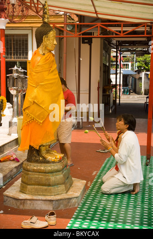 Le donne in preghiera nella parte anteriore del Buddha dorato statua, Wat Intharawihan, Banglamphu, Bangkok, Thailandia Foto Stock