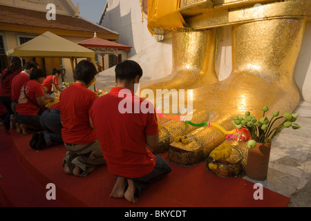 Persone in preghiera di fronte al dorato statua del Buddha, 32 m. alto, Wat Intharawihan, Banglamphu, Bangkok, Thailandia Foto Stock