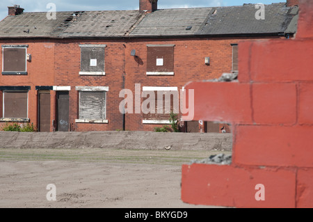 Fila di intavolato case a schiera in attesa di demolizione.East Manchester,Inghilterra.parzialmente demolito proprietà in primo piano. Foto Stock