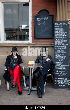 Coppie gotica;coppia, in abiti fantasiosi, sat al di fuori di un pub bar, dove il cibo & bevande è servita a Whitby Goth Festival Weekend, North Yorkshire, 2010 Foto Stock