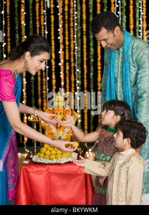 Donna dando dolci ai suoi figli a Diwali Foto Stock