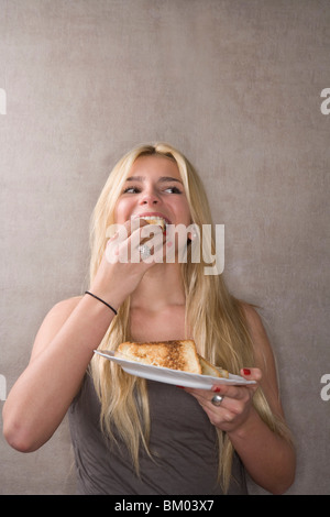 Giovane donna mangia panino Foto Stock