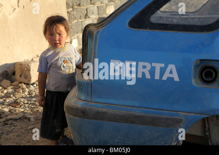 Un bambino mongolo sembra un round abondoned Mongol Rally 2009 Skoda Felicia auto in Mongolia. Foto Stock