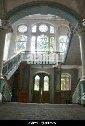 Grande entrata con grandi finestre e una scala nel vecchio ospedale in disuso Foto Stock