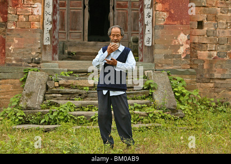 Master dimostra di Taichi movimenti, nella parte anteriore della sua vecchia casa al di sotto del picco, Wudang Shan, taoista di montagna, provincia di Hubei, Wu Foto Stock