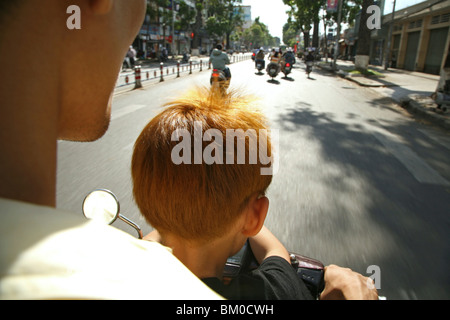 Padre e figlio la guida ciclomotore, a Saigon, Ho Ch Minh City, Vietnam, Asia Foto Stock