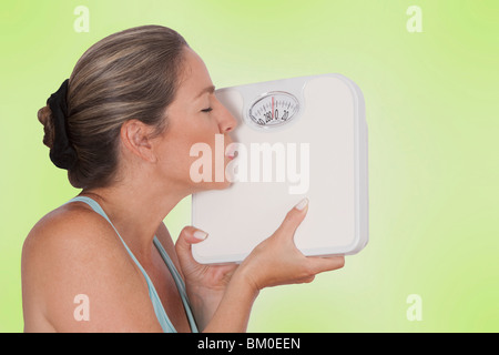 Close-up di una donna baciare una bilancia da bagno Foto Stock