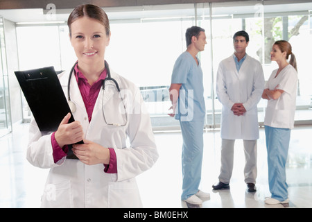 Medico donna tenendo un appunti con i suoi colleghi a discutere in background Foto Stock