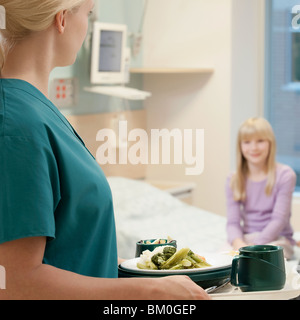 Infermiera femmina tenendo il pasto con un paziente in background Foto Stock