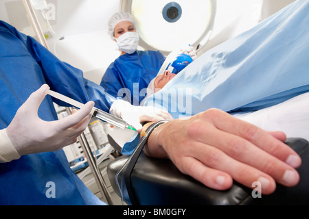 Medico iniettando il braccio del paziente in sala operatoria Foto Stock