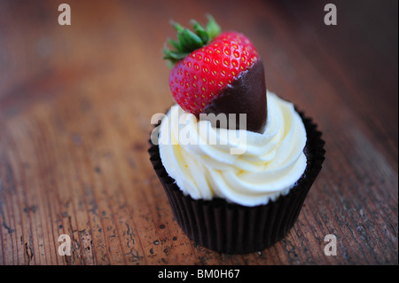 Una tortina fatta dalla spugna di cioccolato guarnita con panna e una fragola Foto Stock