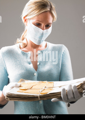 Donna con maschera, tenendo i file preziosi Foto Stock