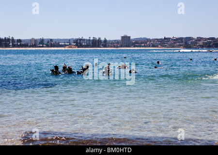 Una classe di immersioni a Shelly Beach, con il Sud Steyne beach in background. Foto Stock