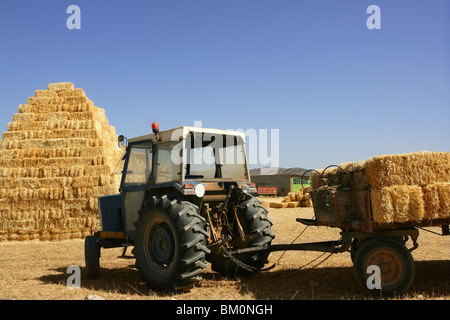Fienile impilato con piramyd forma e agricoltura del veicolo trattore Foto Stock