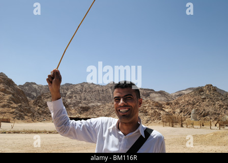 Giovane uomo egiziano con bastone nel villaggio beduino vicino a Hurghada, Egitto Foto Stock