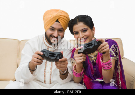 Ritratto di un giovane sikh azienda video controller di gioco e sorridente Foto Stock