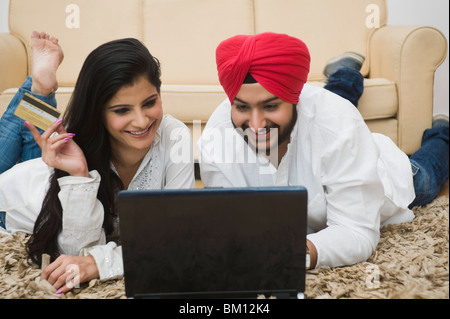 La religione sikh giovane in possesso di una carta di credito e al lavoro su un notebook Foto Stock