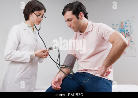 Medico donna uomo di controllo della pressione del sangue Foto Stock