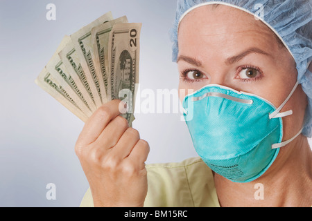 Medico donna azienda moneta note Foto Stock