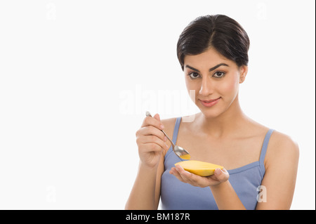 Ritratto di una donna di mangiare il mango con un cucchiaio Foto Stock