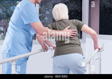 Lavoratore di salute assistere una donna disabile nel camminare Foto Stock