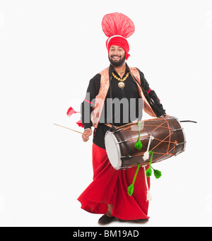 Uomo di eseguire la danza Bhangra con dholak Foto Stock