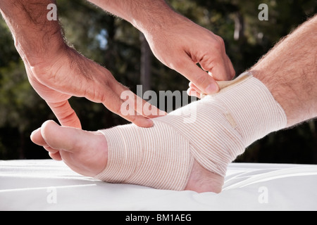 Medico di legatura bendaggio crêpe su un piede di un paziente Foto Stock